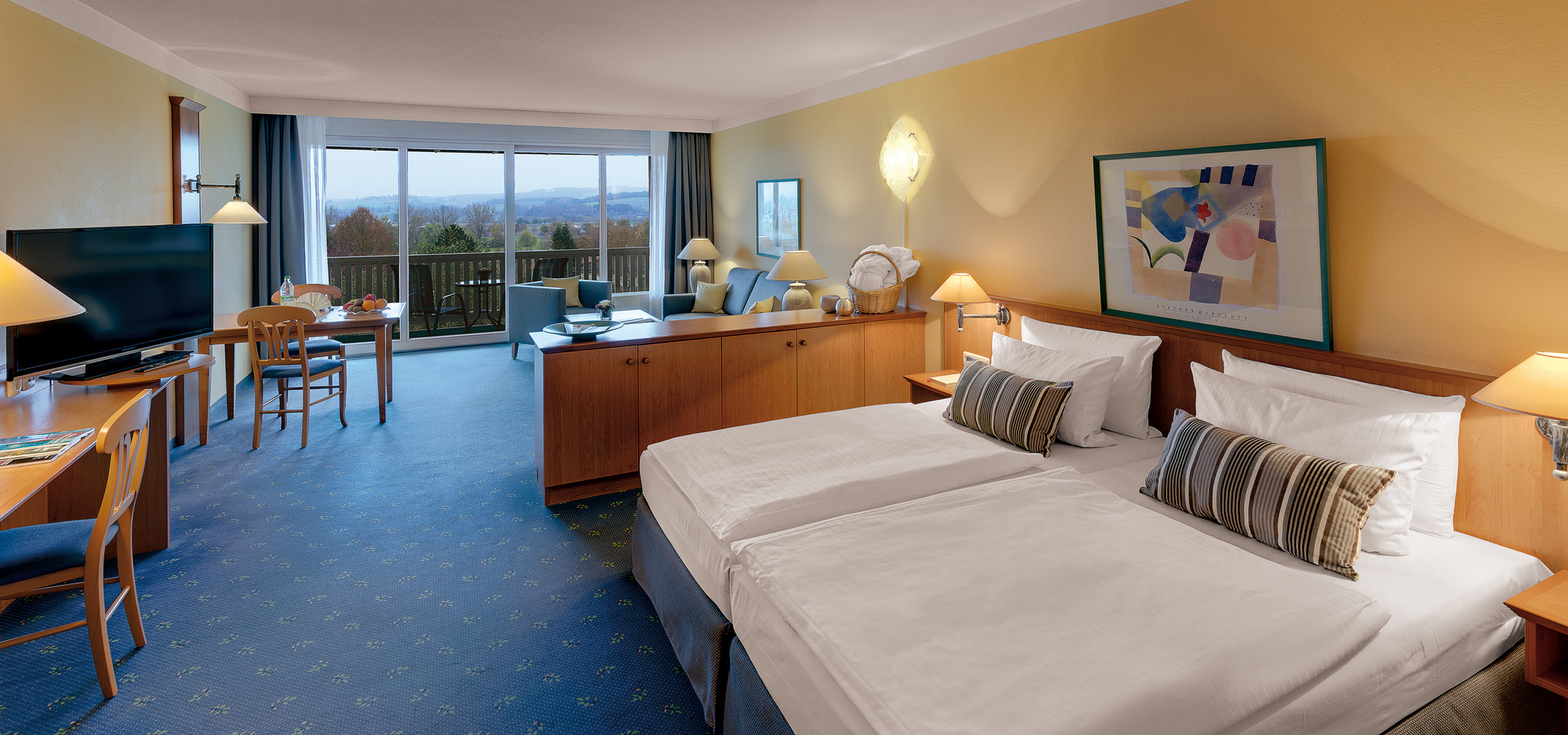  Geräumiges Zimmer mit zwei Betten, Schreibtisch, Sitzbereich und großem Fenster mit Ausblick.